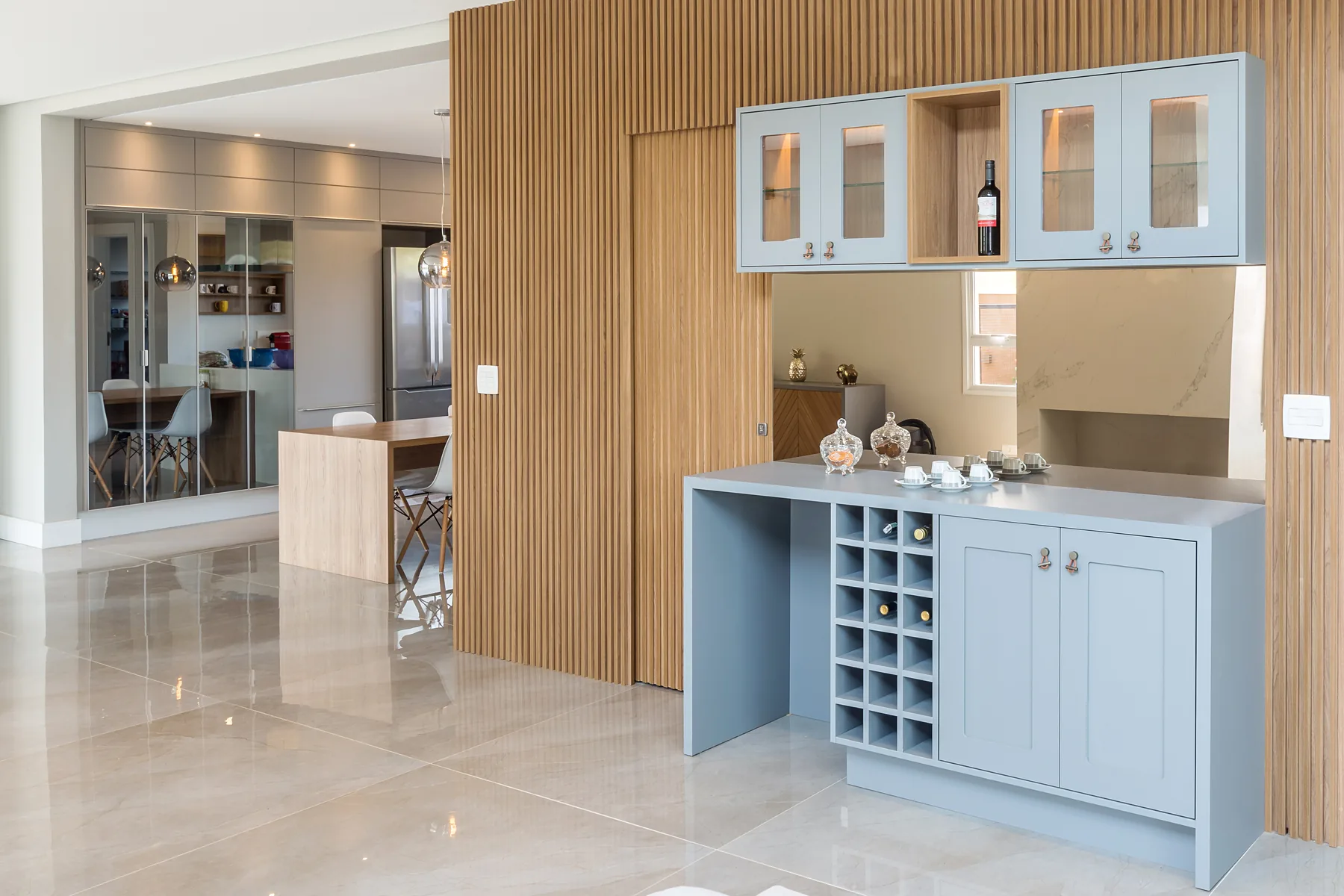 Bar e adega planejada sob medida em azul serenity com porta-vinhos, portas de vidro e painel ripado de madeira, em Atibaia