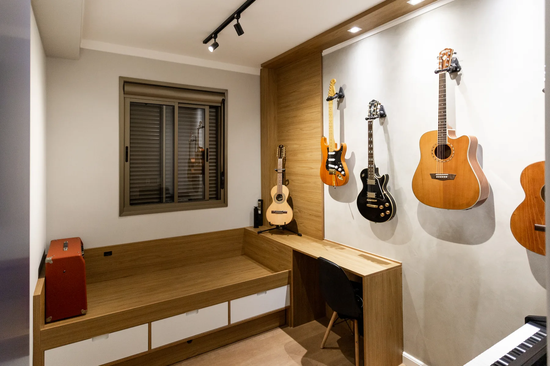 Escritório e sala de música planejada com bancada de madeira, banco baú e suporte de guitarras na parede, projeto Casa & Design em Atibaia