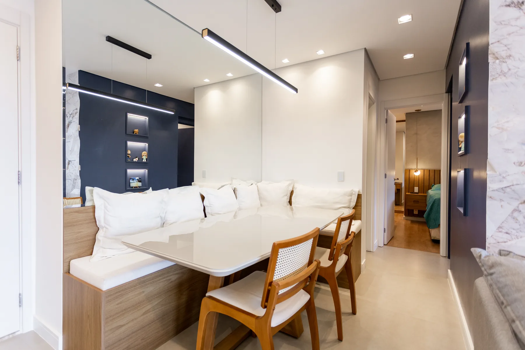 Sala de jantar planejada com banco baú, mesa e espelho ampliando o ambiente, projeto em Atibaia